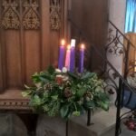 Corona de Adviento con velas encendidas en una iglesia