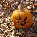 Calabaza tallada de Halloween rodeada de hojas de otoño