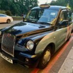 Taxi negro tradicional británico circulando por una calle de Londres